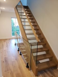 Elegant glass railing system installed on wood staircase in Toronto home by Belka Glass, meeting Ontario Building Code safety standards for kids and pets.
