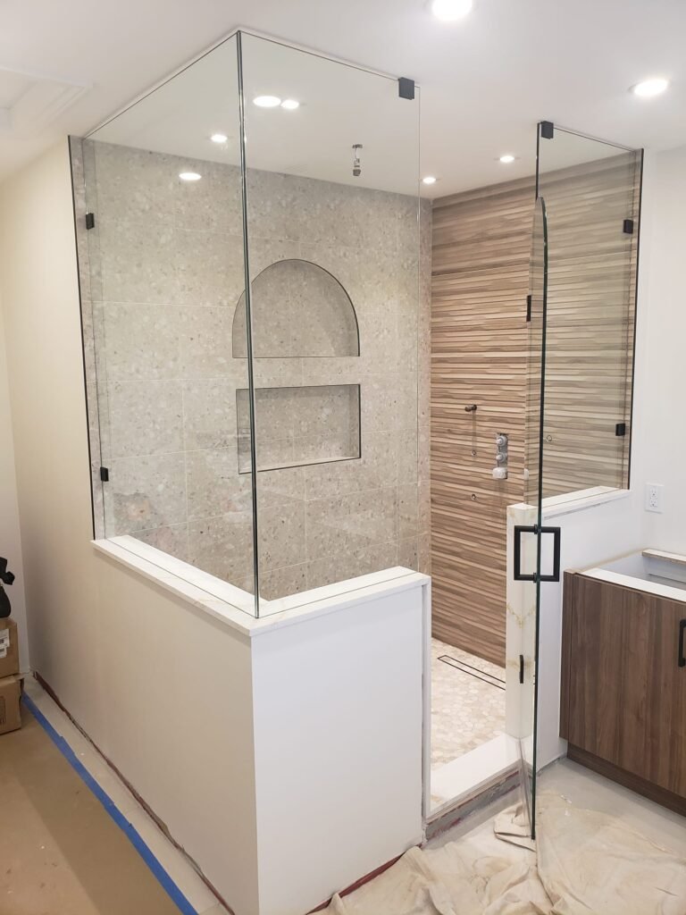 A custom glass enclosure made for a bathroom renovation with a knee wall