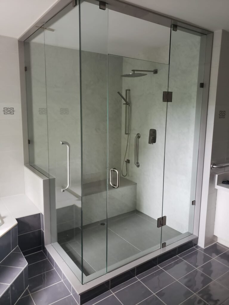 Frameless custom glass shower enclosure with chrome hardware and built-in bench, installed by Belka Glass in a modern Toronto bathroom.