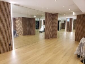 A sleek gym space featuring custom wall-to-wall mirrors with integrated LED lighting, enhancing the workout environment with a spacious and modern design