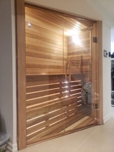 Frameless glass enclosure for a home sauna with warm wood interior, installed by Belka Glass in Toronto.