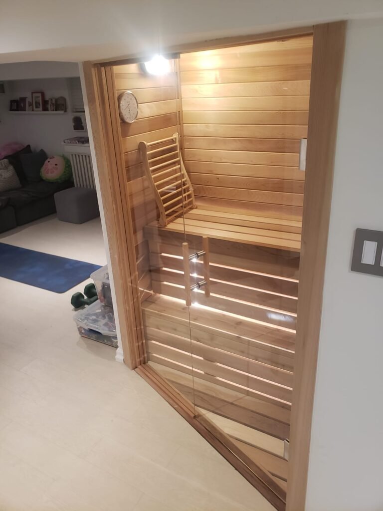 Side view of custom glass sauna enclosure showcasing modern design and seamless integration with cedar wood walls, Toronto installation by Belka Glass.
